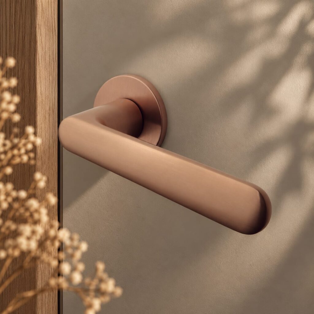 Klamka Aprile Aria R 5S w wykończeniu miedziany mat, na okrągłej rozecie Super Slim 5 mm – aranżacja w stylu loftowym z naturalnym drewnem, beżami i ciepłym oświetleniem.